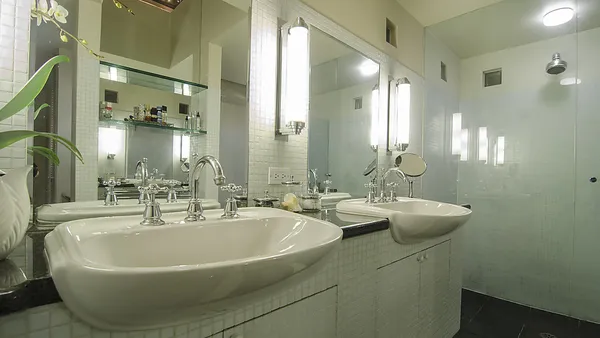 Ensuite bathroom with double undermount sinks, polished chrome fixtures, backlit mirrors and glass shower enclosure — bathroom renovation West Vancouver by DELANA Interiors