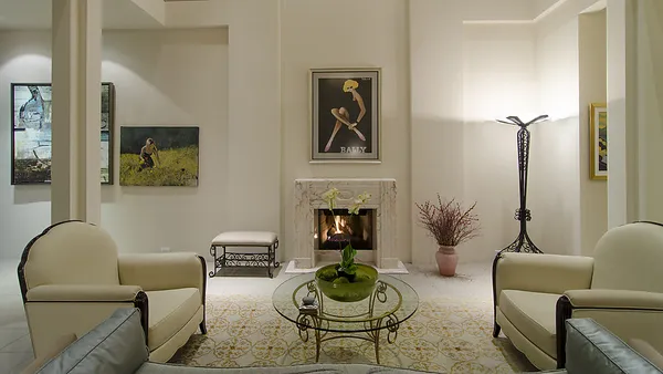 Grand living salon with white marble fireplace centred between paired upholstered armchairs and traditional Bally artwork — custom home building West Vancouver by DELANA Interiors