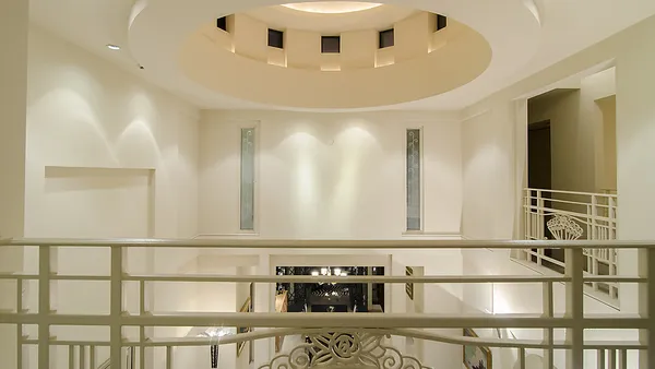 Custom domed rotunda ceiling above upper hallway with wrought-iron balustrade and recessed cove lighting — custom home building West Vancouver