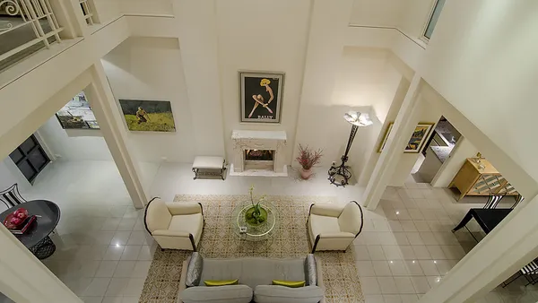 Overhead view of double-height formal living salon with marble fireplace, traditional artwork and symmetrical seating — custom home building West Vancouver by DELANA Interiors