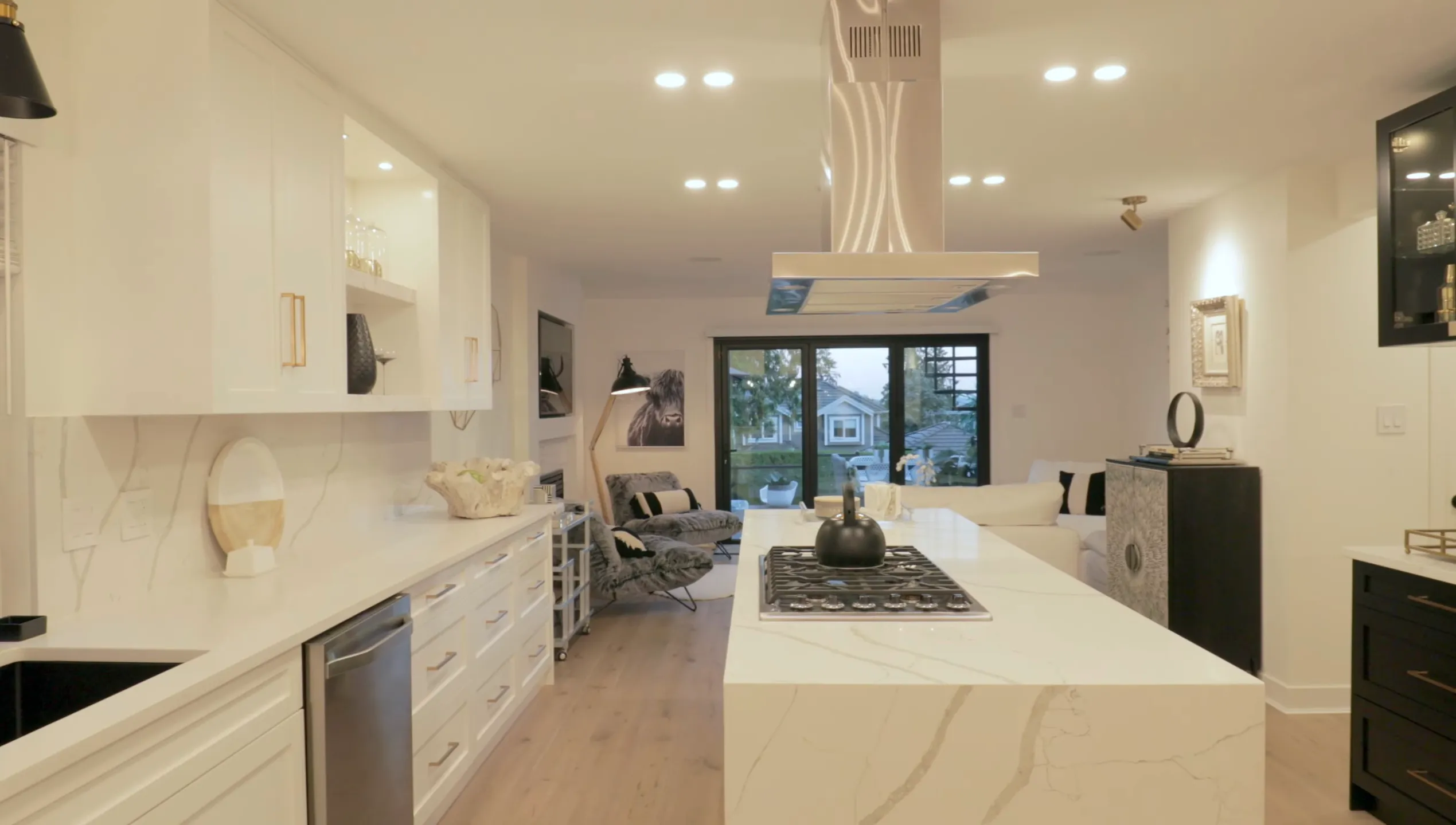 Renovated open-plan kitchen with white shaker cabinetry, Calacatta marble waterfall island, stainless steel range hood and adjoining living area with garden view — kitchen renovation Vancouver by DELANA Interiors