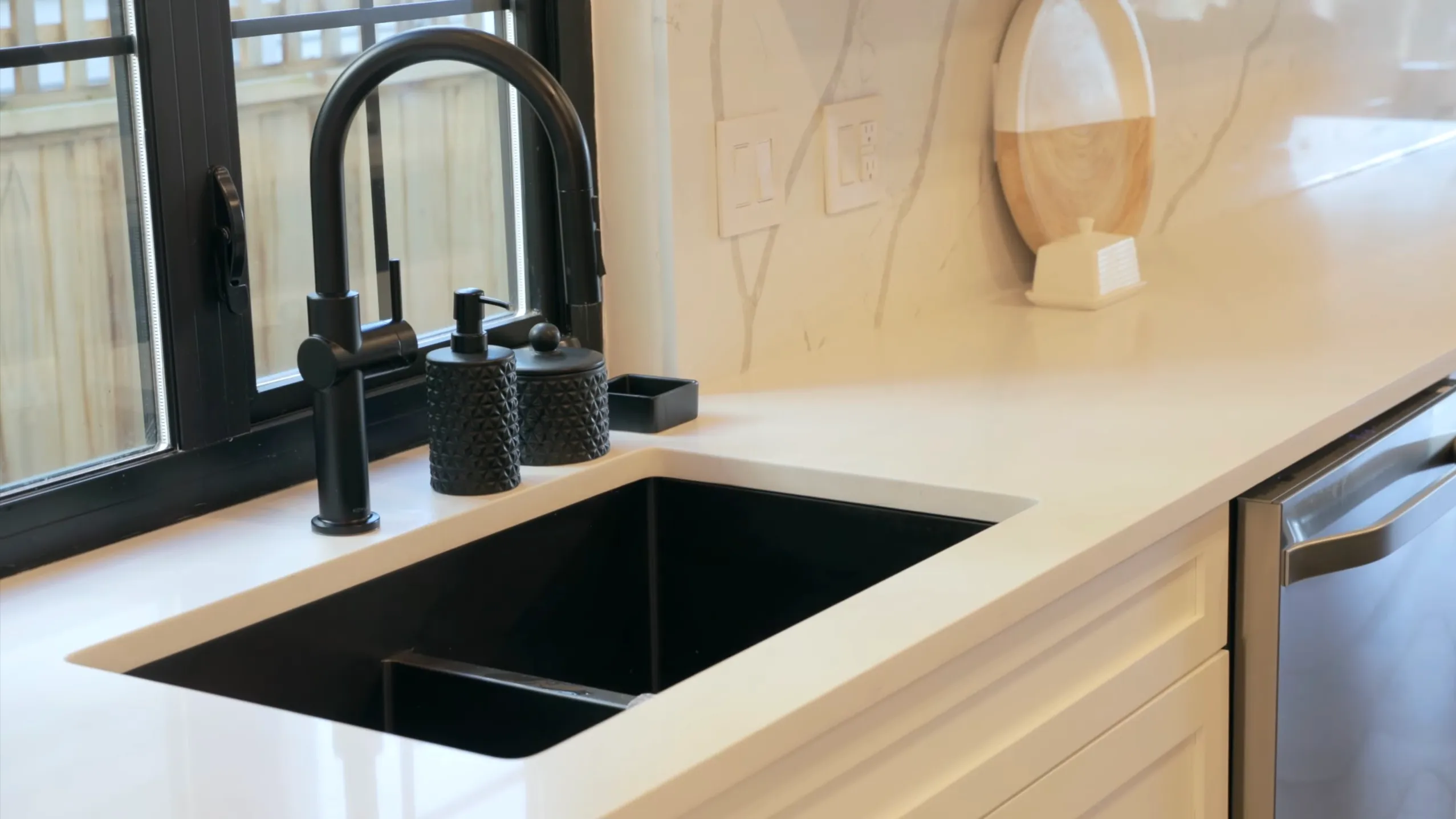Renovated kitchen undermount black composite sink with matte black faucet, Calacatta quartz countertop and integrated dishwasher — kitchen renovation Vancouver by DELANA Interiors