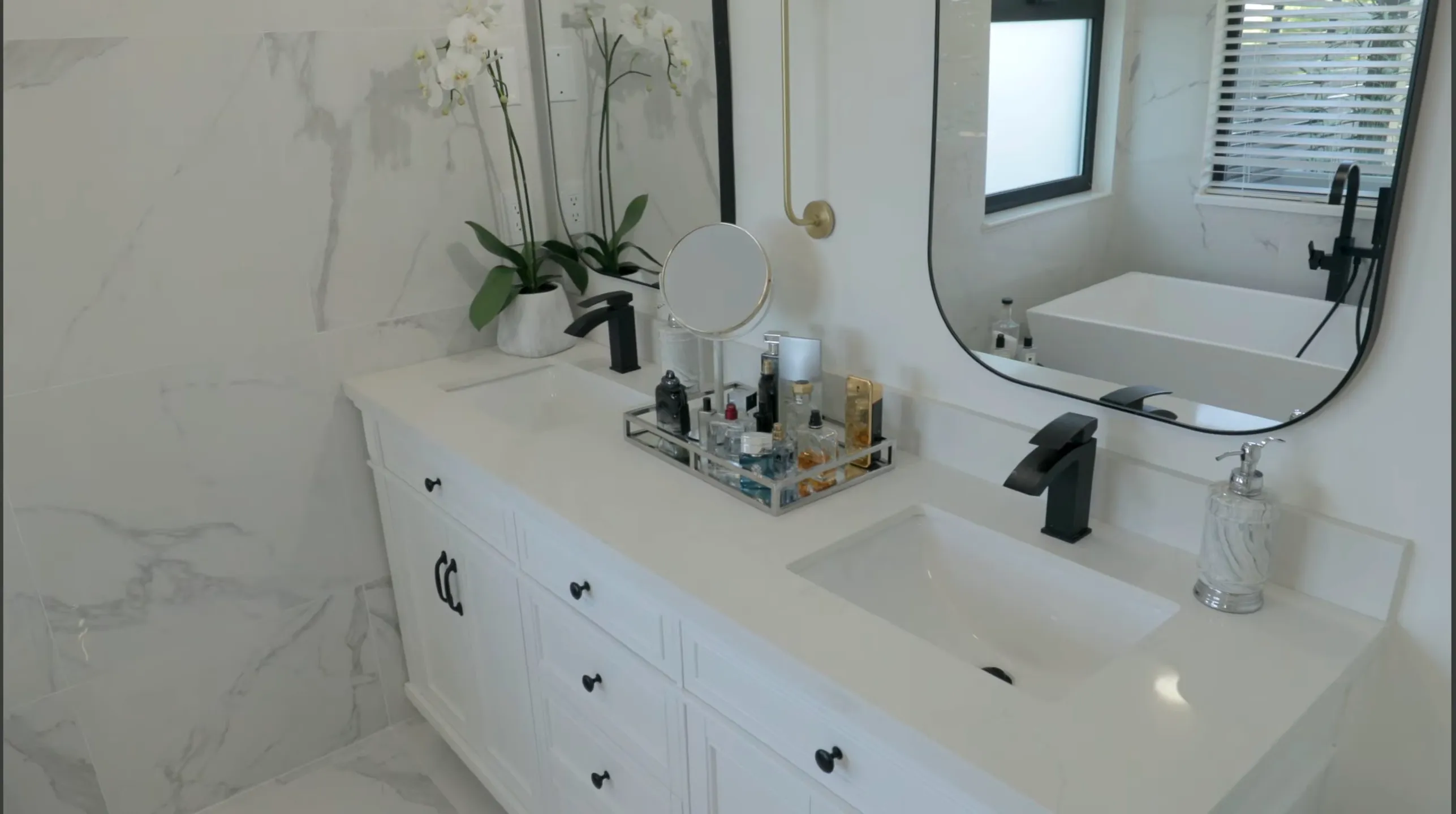 Renovated ensuite bathroom with double vanity, marble countertop, black framed mirrors, matte black fixtures and marble tile surround — bathroom renovation Vancouver by DELANA Interiors