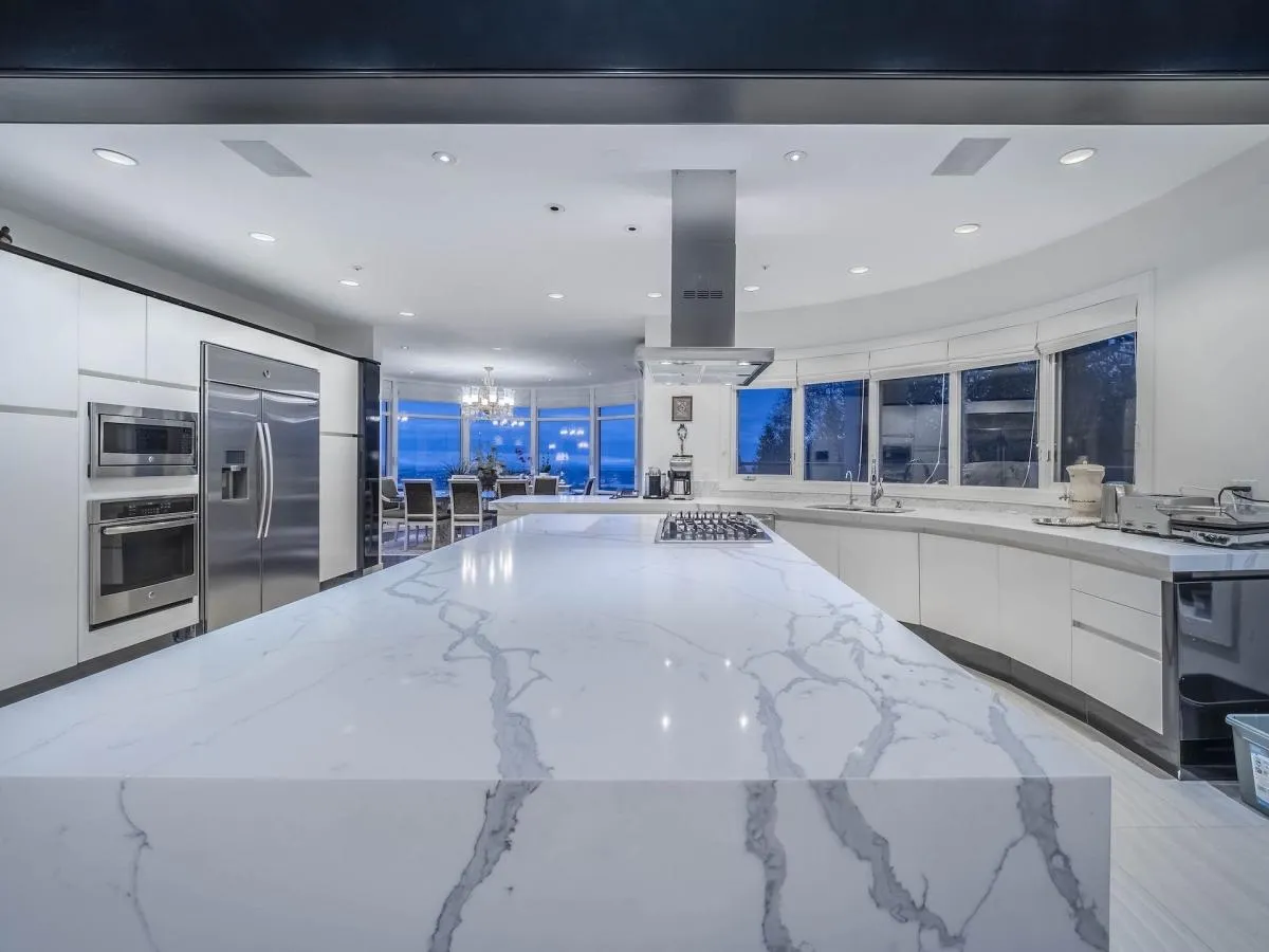 Renovated kitchen with Calacatta marble waterfall island and curved ocean-view window wall at 1588 Pinecrest Drive, West Vancouver — DELANA Interiors