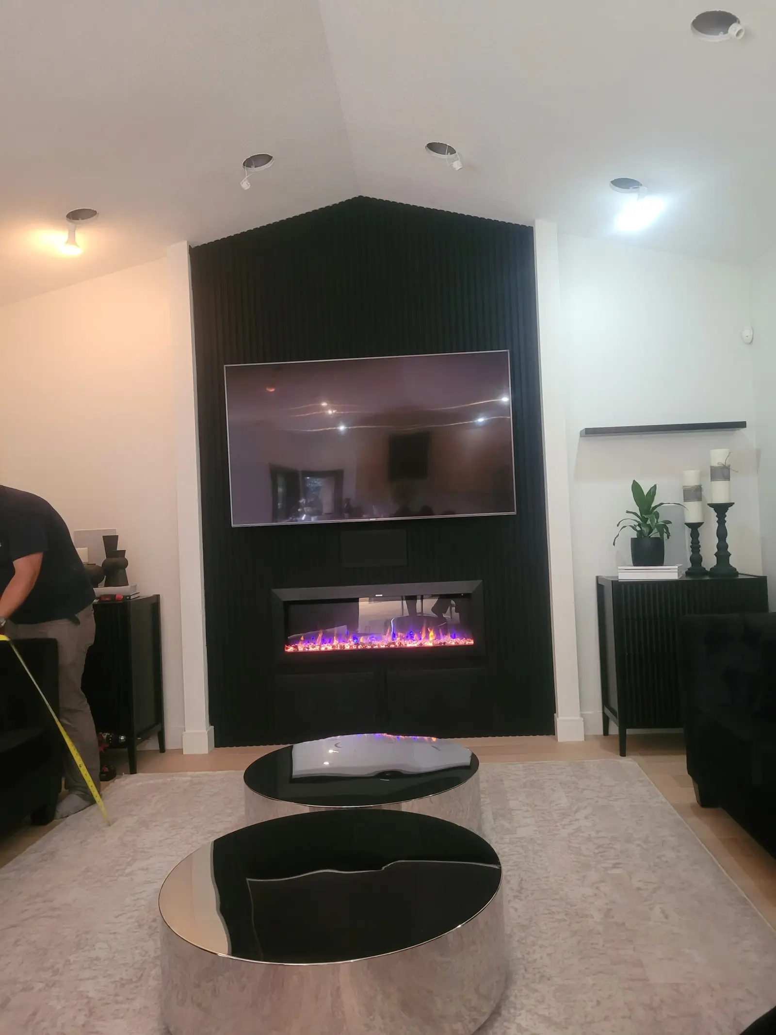 Modern living room feature wall with black fluted panels, wall-mounted TV and electric fireplace — home renovation Vancouver