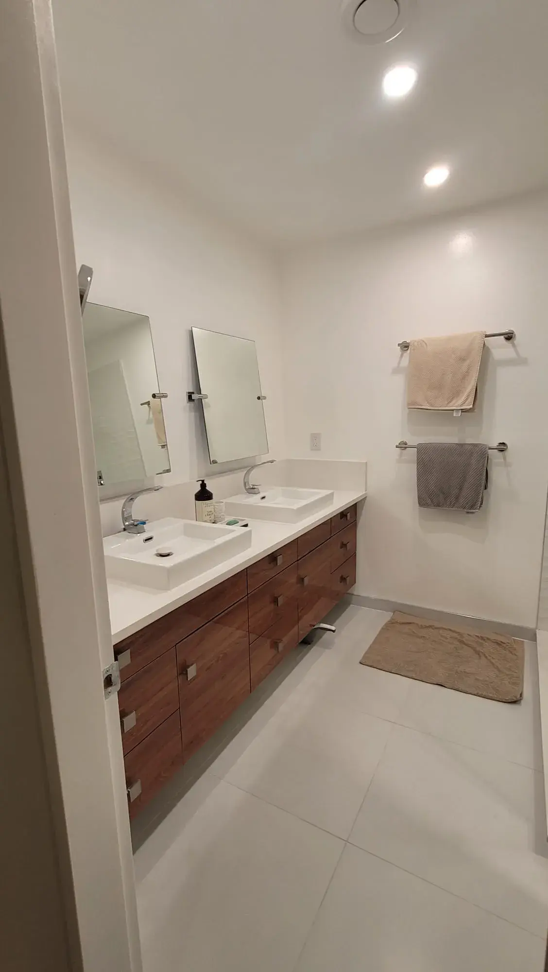 Double sink bathroom with walnut cabinets, white quartz countertop and adjustable pivot mirrors — bathroom renovation Vancouver