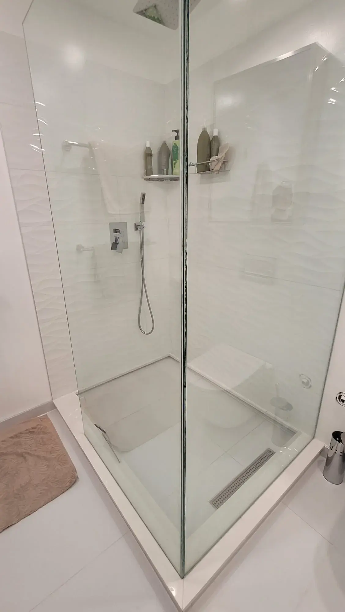 Walk-in shower with frameless glass enclosure, chrome rainfall fixture and linear floor drain — bathroom renovation Vancouver