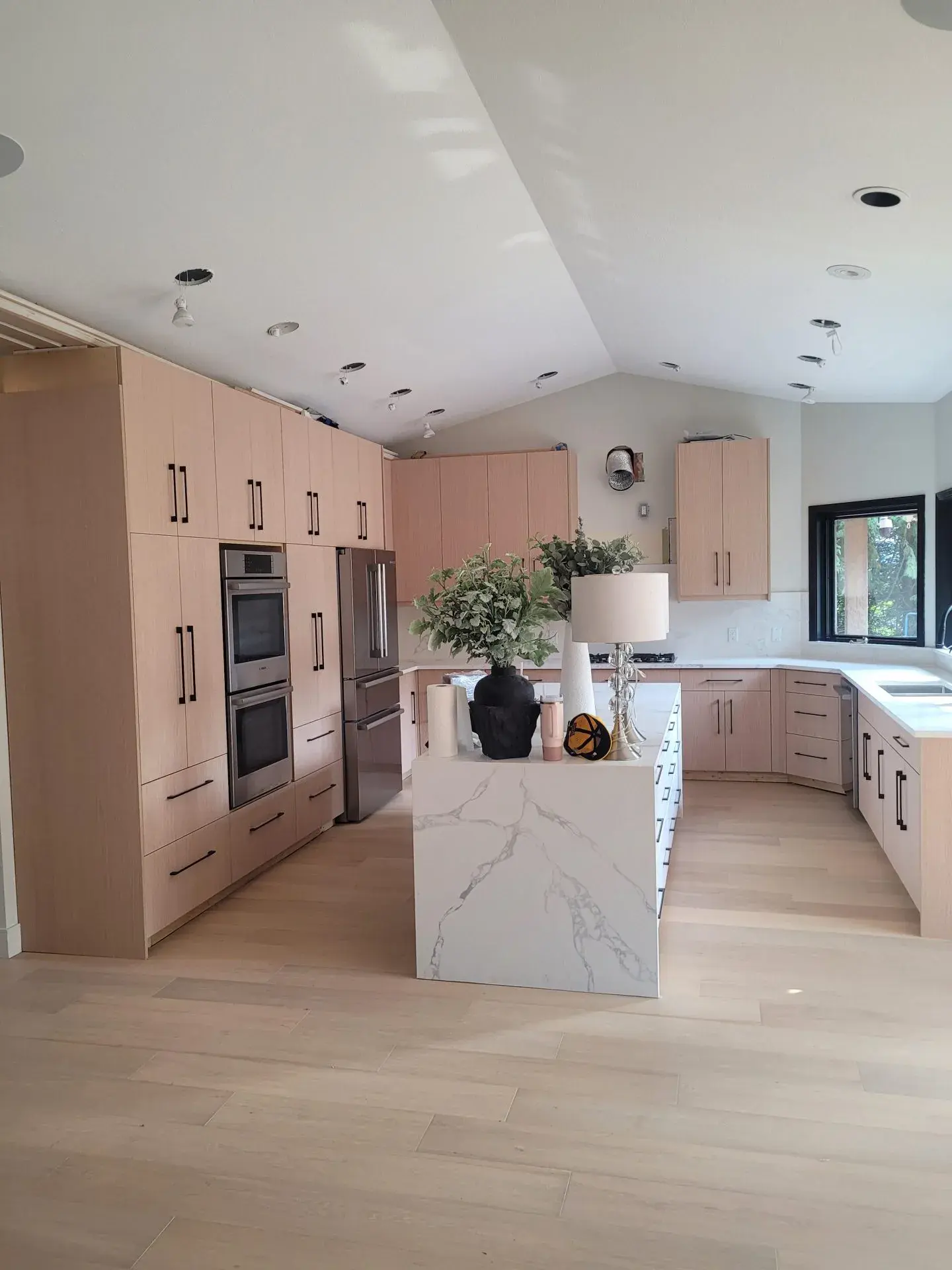 Custom light oak kitchen with waterfall quartz island and double wall ovens — kitchen renovation Vancouver