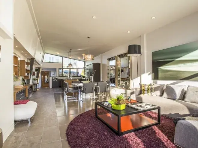 Open-plan living and dining area with double-height ceilings and kitchen visible in background — luxury home renovation Vancouver