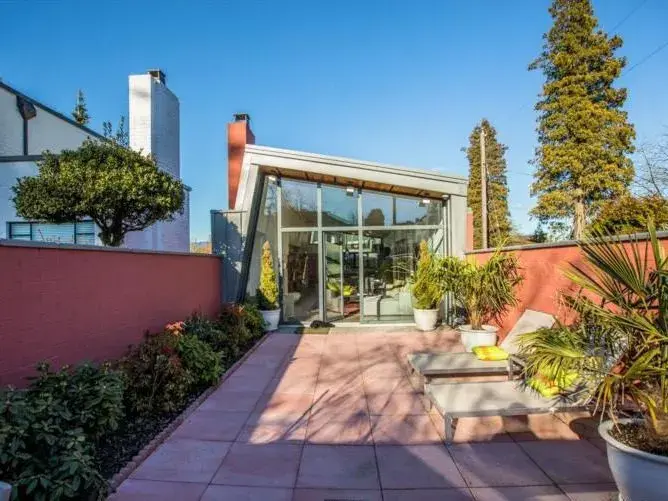 Private landscaped patio with angled glass wall extension and tropical garden — outdoor renovation Vancouver